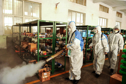 Voluntarios desinfectan un área administrativa ante el brote del coronavirus en Shandong, China. 