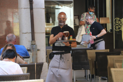 Un camarero con mascarilla y pantalla de seguridad en la cara, en una terraza en Figueres.
