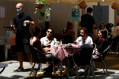 Diversos joves gaudeixen d’un vermut en una terrassa del Poble Sec a Barcelona.