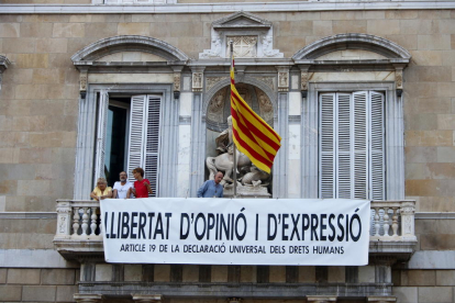 El cantautor i exdiputat Lluís Llach, l'actriu Sílvia Bel, el periodista i exdiputat Antoni Baños i la portaveu de Somescola, Teresa Casals, col·loquen una nova pancarta al balcó del Palau de la Generalitat.