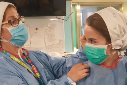Una sanitaria ayuda a otra a colocarse la mascarilla en un centro de Lleida.