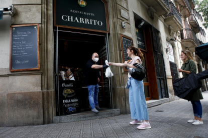 Unas clientas recogen comida para llevar en un establecimiento de Barcelona.