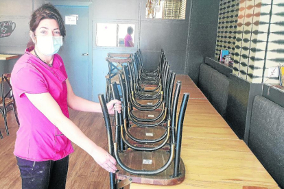 El dueño de un bar restaurante de Lleida prepara el interior del local con mamparas entre las mesas.