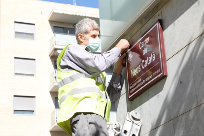 Un operario coloca la placa con el nombre de Neus Català. 