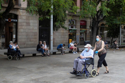 Una dona passeja un home pels carrers de Barcelona equipats amb mascaretes.