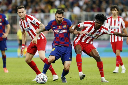 Messi, que volvió a hacer un gran partido, intenta irse del marcaje de los rojiblancos Saúl y Thomas.