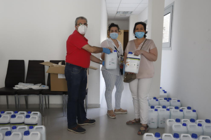 A l’esquerra, el president de l’Eix, Llorenç González, entrega el kit sanitari a una comercianta. A la dreta, una dona surt d’una botiga que ofereix serveis de cita prèvia.