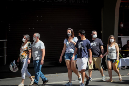 Personas con mascarillas para prevenir a propagación del coronavirus caminan en la avenida Paulista en Sao Paulo (Brasil)