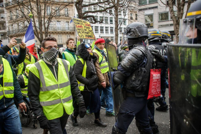 Miembros de los “chalecos amarillos”, ayer, ante las fuerzas del orden en las calles de París.