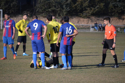 Un jugador lesionado del Juneda es rodeado por varios compañeros y rivales en presencia del árbitro del encuentro.