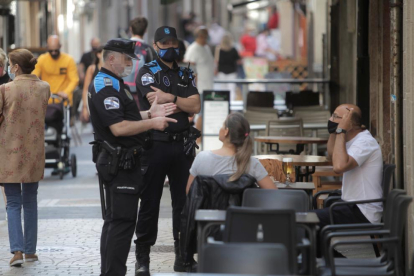 Dos policías locales de A Coruña informan de las restricciones a un fumador en una terraza.