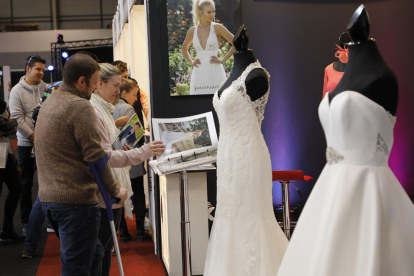 Visitants s’interessen pels catàlegs de vestits de núvia d’un dels expositors de la fira.