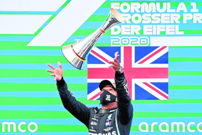Hamilton celebra su victoria número 91 lanzando el trofeo al aire.