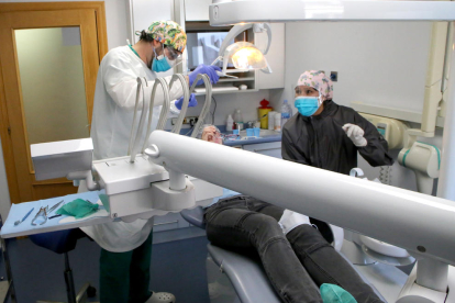 Dos profesionales de una clínica dental de Lleida ciudad atendiendo a un paciente ayer por la tarde.