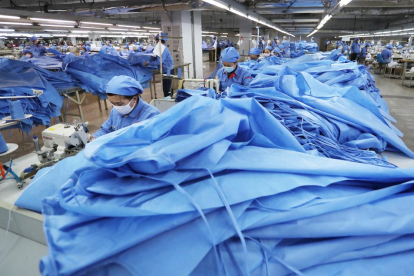 Empleats amb màscares confeccionen camises d’aïllament al comtat de Zouping (Xina).