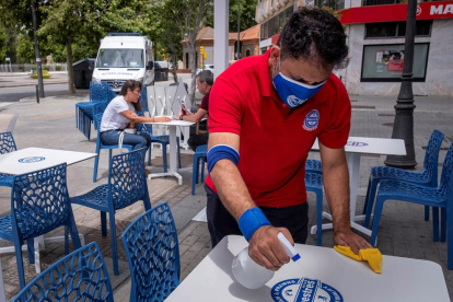Un cambrer desinfecta les taules d’una terrassa en un bar de Huelva.