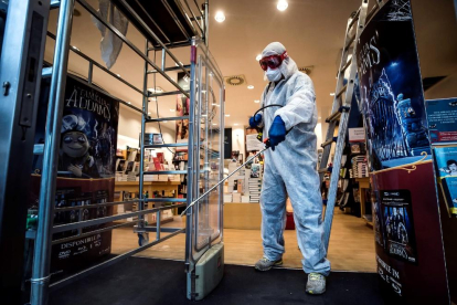 Un trabajador desinfecta una librería en Roma, negocios que Italia permite reabrir ya.