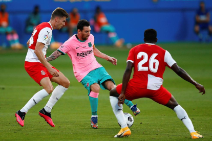 Leo Messi controla la pilota davant de Gumbau i Ibrahim Kebe, jugadors del Girona.