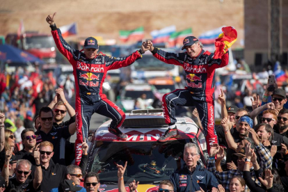 Carlos Sainz i el seu copilot, Lucas Cruz, celebren el triomf al Dakar a damunt del seu vehicle.