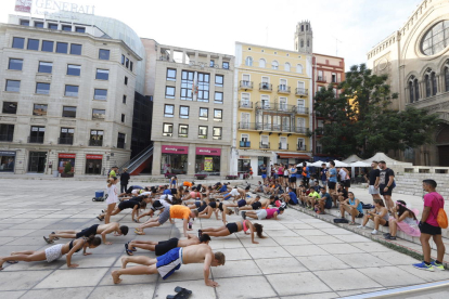Alumnes bevent i fent flexions com a part de les novatades, ahir a la plaça Sant Joan.