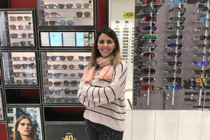 Una empleada de una óptica de Lleida enseña varias gafas a una clienta.