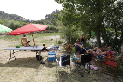 Mesas de picnic, tumbonas y sombrillas en la ribera del río Segre en Camarasa. 