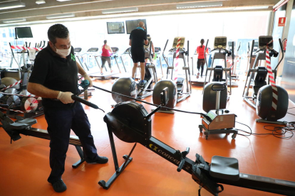 Un operario del gimnasio Trèvol desinfecta una máquina de fitness.