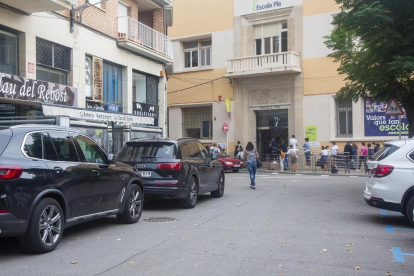 Imagen de grupos de padres esperando ante las puertas de sendos colegios de Lleida esta semana. Ahora, los centros no les permiten entrar en sus patios.