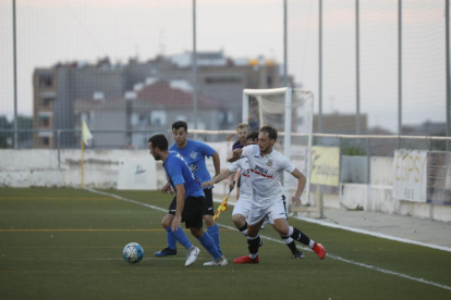 Un jugador de l’Alcarràs protegeix la pilota, perseguida per dos futbolistes del Borges.
