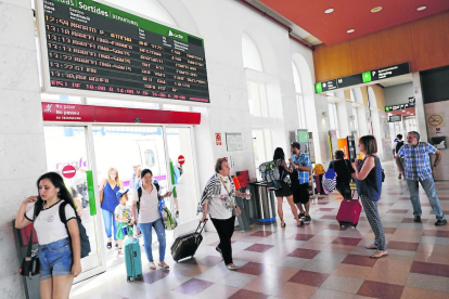 Varios pasajeros llegan a la estación de Lleida-Pirineus mientras otros miran el panel de salidas, que registraba dos trenes anulados. 