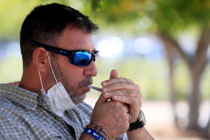 Un fumador se enciende un cigarrillo en un parque madrileño.
