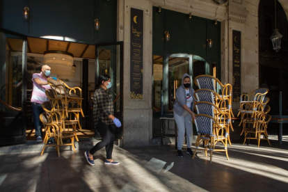Dos trabajadores recogen la terraza de un bar del centro de Barcelona.
