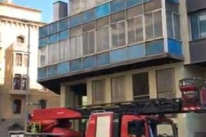 El bombers sanegen la façana de l'edifici dels sindicats de Lleida, amb un panell de vidre a punt de caure