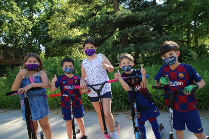 Varios niños jugando ayer con patinete por calles de Lleida llevando mascarillas infantiles