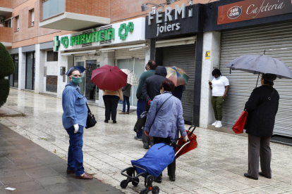 Ciudadanos haciendo cola ante una farmacia de Lleida en una imagen de archivo.