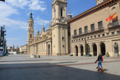 Una mujer pasea a un perro en Zaragoza por una plaza del Pilar completamente vacía. 