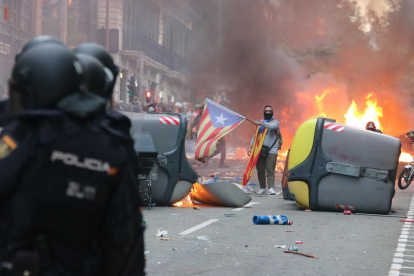 Agentes de la Policía Nacional, ayer en Via Laietana frente a una barricada de contenedores y un manifestante con una estelada.