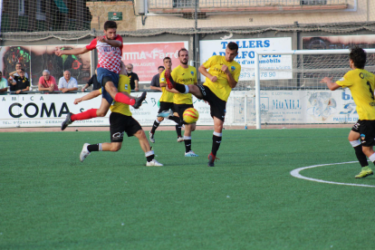 Un jugador del Balaguer colpeja la pilota envoltat de rivals que miren d’impedir que dispari a porta.