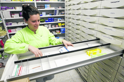 Una empleada d'una farmàcia a Pardinyes mostra els calaixos buits de medecines.