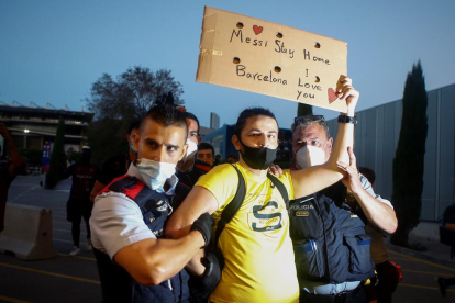 Dos agentes de los Mossos detienen ayer a uno de los manifestantes contra la junta del Barça.
