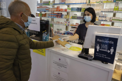 Una farmacéutica entrega una mascarilla de la Generalitat a un ciudadano el pasado lunes. 