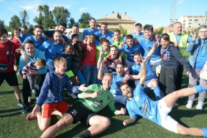 Els jugadors de l’Alcarràs celebren el campionat a la gespa després del partit.