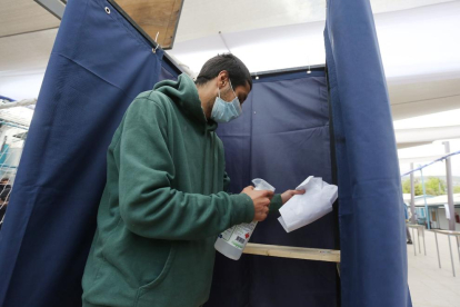 Un home desinfecta una cabina de votació en un col·legi electoral a Santiago de Xile.