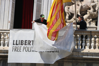 Dos treballadors de la Generalitat retiren els llaços del Palau
