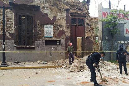 Operaris retiren runa d’un edifici afectat pel sisme.