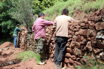 Personas reparando un trozo de pared de piedra seca en la ruta del Quinto Lago.
