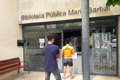 Dos usuarios de la Biblioteca Pública de Tremp esperando ayer su turno  para recoger un libro. 