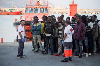 Migrants d’origen subsaharià al costat d’efectius de la Creu Roja després de ser rescatats.