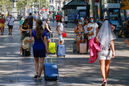 Diverses turistes caminen per la Rambla de Barcelona.