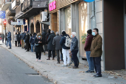 Llargues cues de clients esperant per entrar en una administració de loteria a Lleida, ahir.